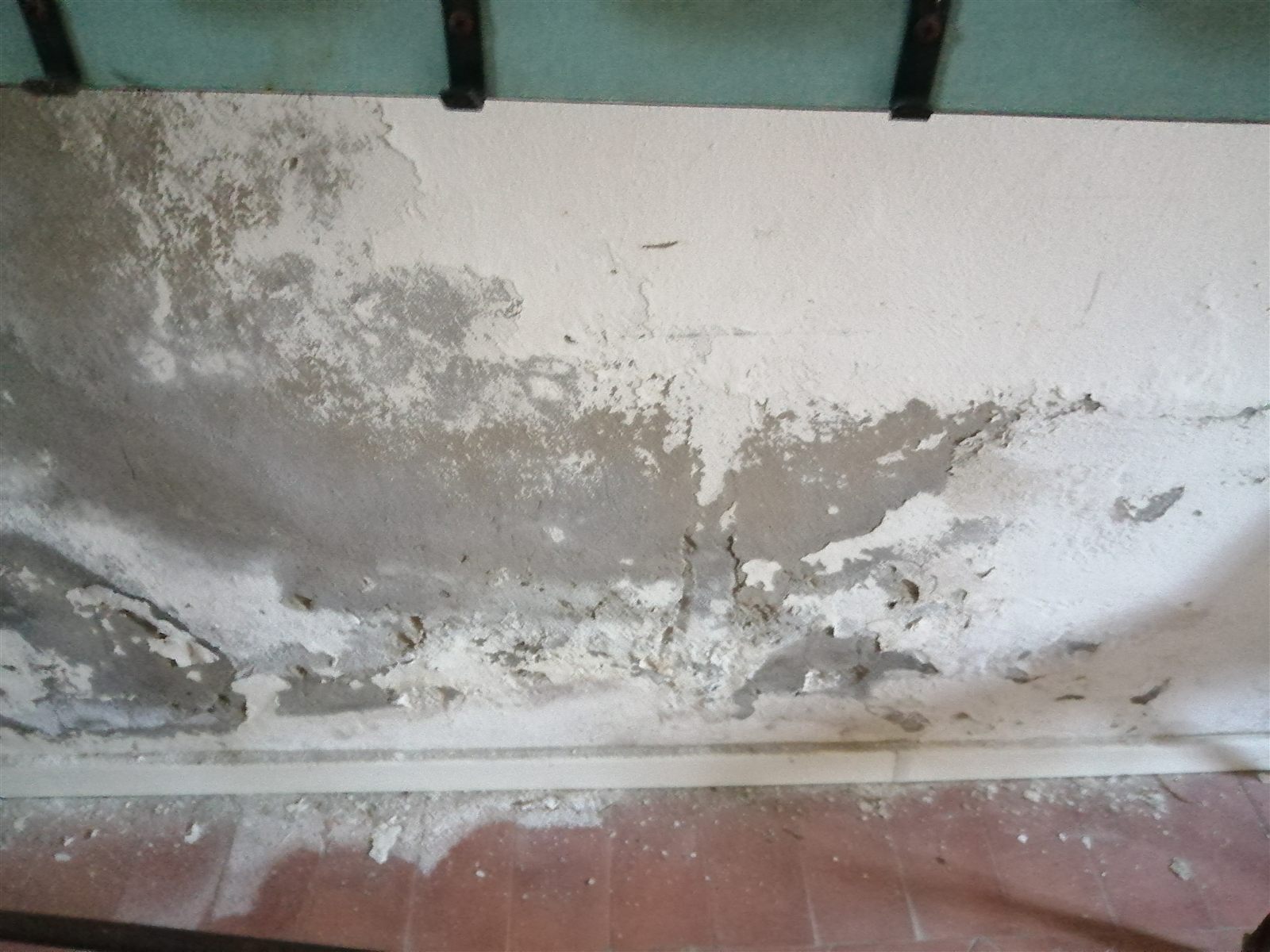 Muro con umidità di risalita: intonaco distaccato ed efflorescenze saline alla base della parete
